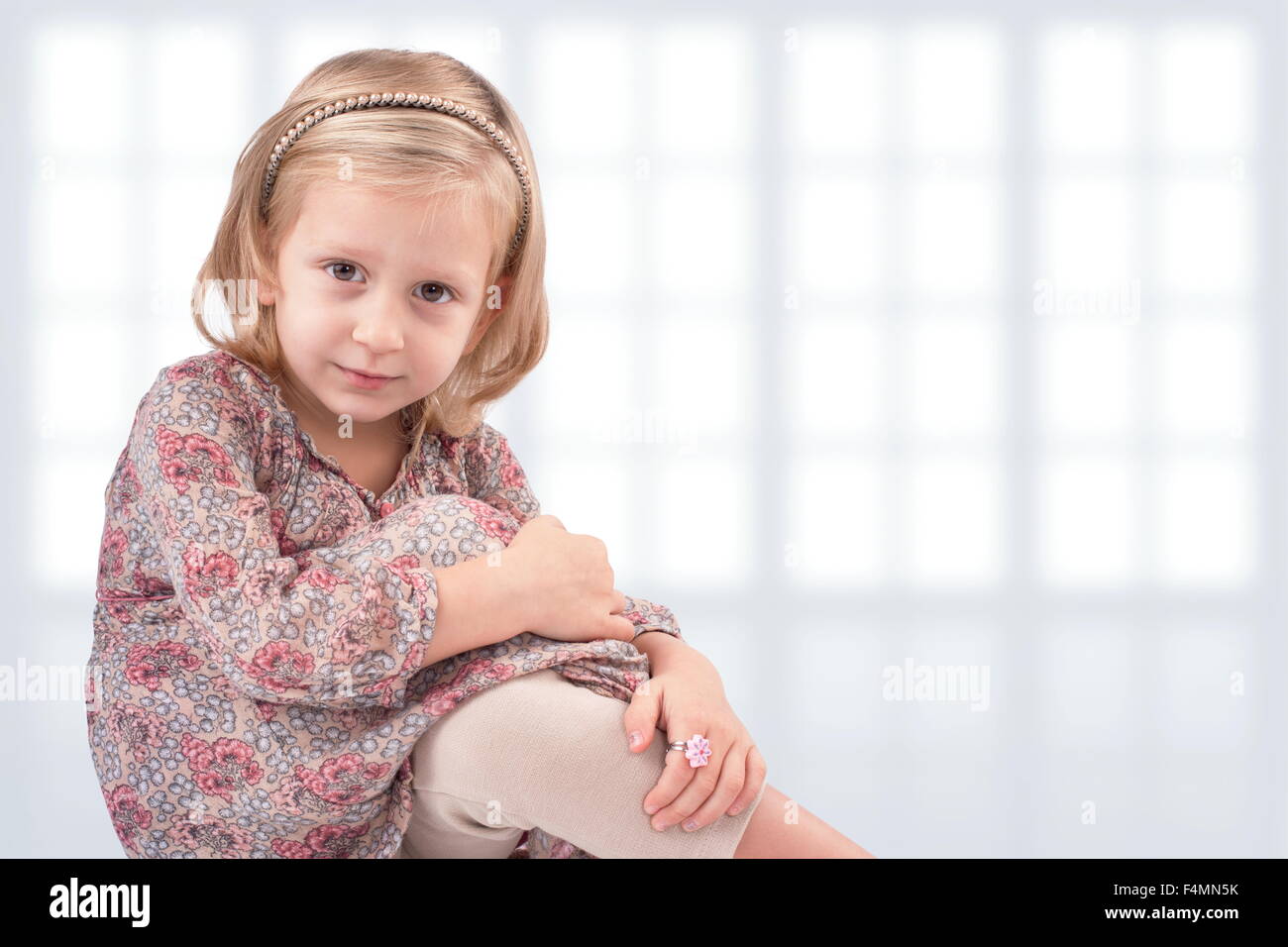 Niedliche kleine Mädchen sitzen vor windows Stockfoto