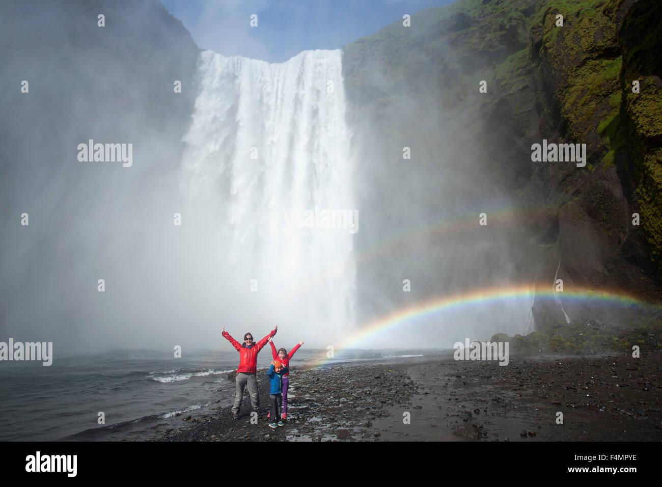 Familie des Regenbogens unter 60m hohen Skogafoss Wasserfall, Skogar, Sudhurland, Island. Stockfoto