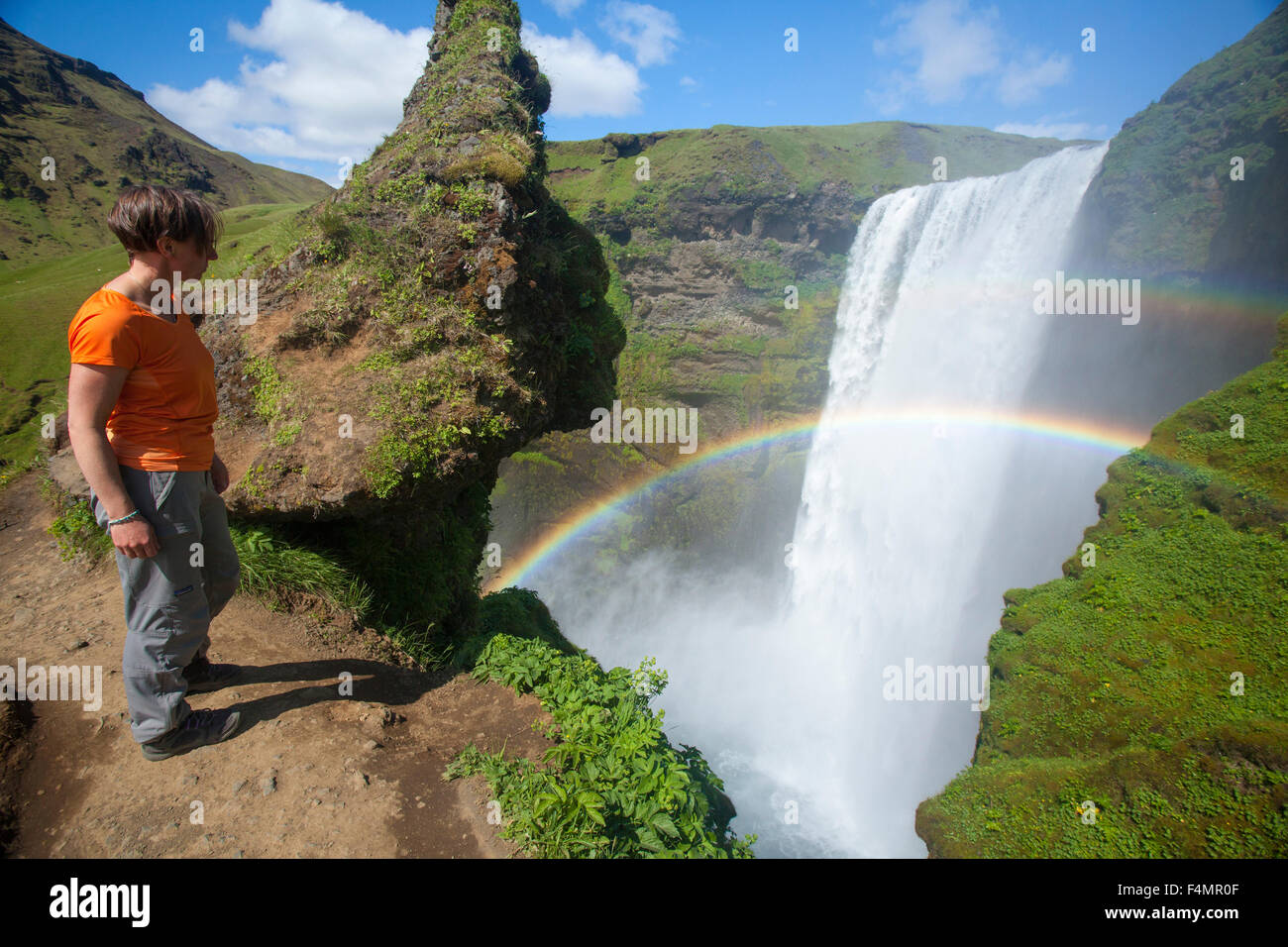 Person, die 60m hohe Skogafoss Wasserfall, Skogar, Sudhurland, Island zu bewundern. Stockfoto