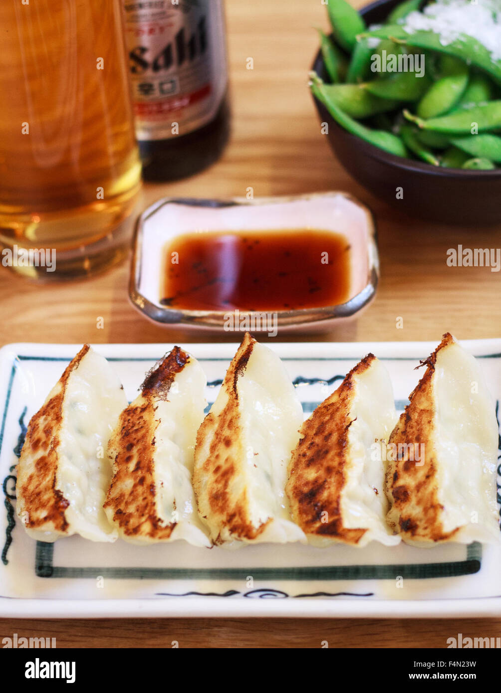 Gegrilltes Huhn Knödel / Dim Sum mit Soja DIP-Sauce, Bier und frisch gekochte Sojabohnen im Hintergrund Stockfoto