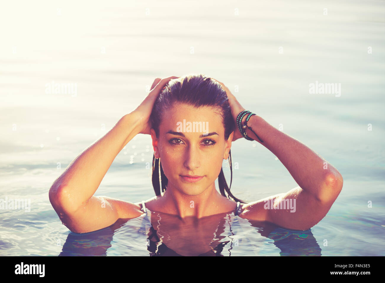 Schöne junge Frau Entspannung im Pool bei Sonnenuntergang, Luxus-Resort-Mode-lifestyle Stockfoto
