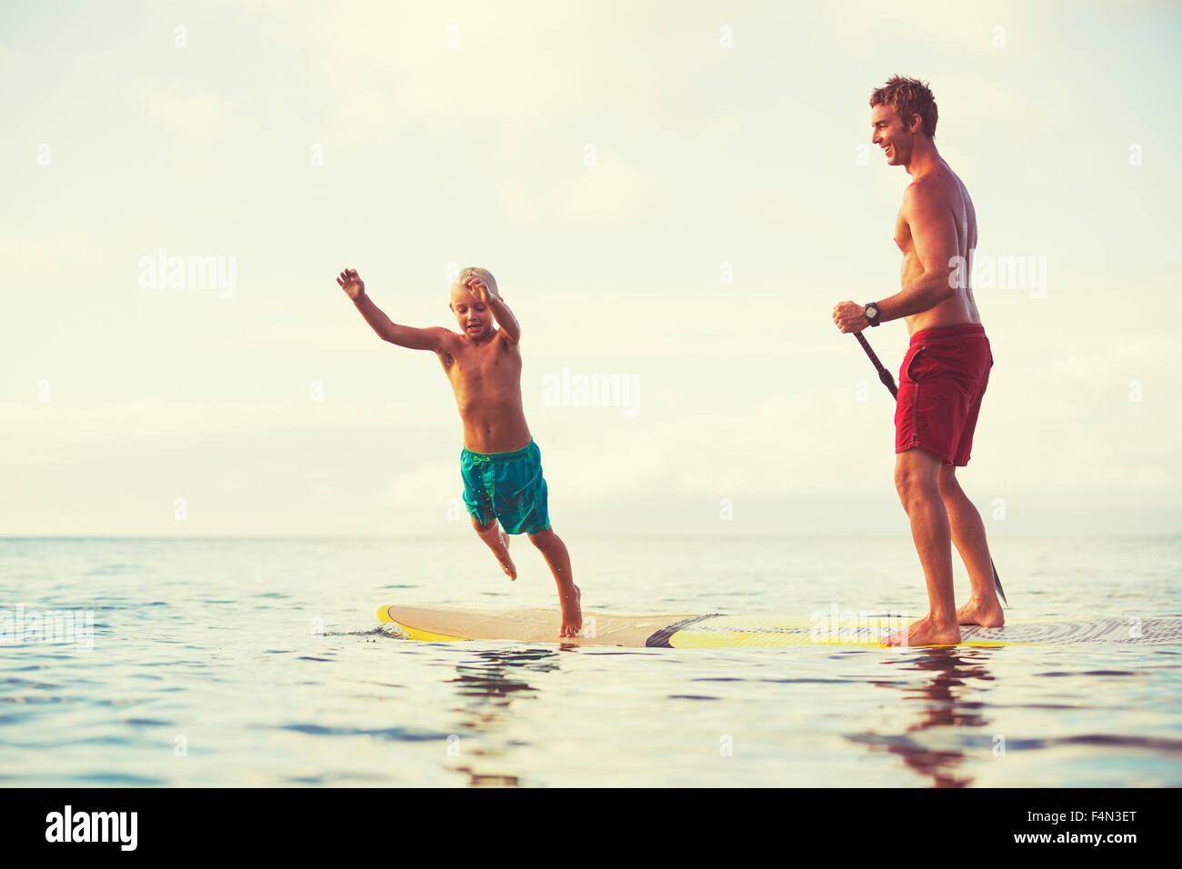 Vater und Sohn aufstehen paddeln bei Sonnenaufgang, Sommer Spaß outdoor-Lifestyle Stockfoto