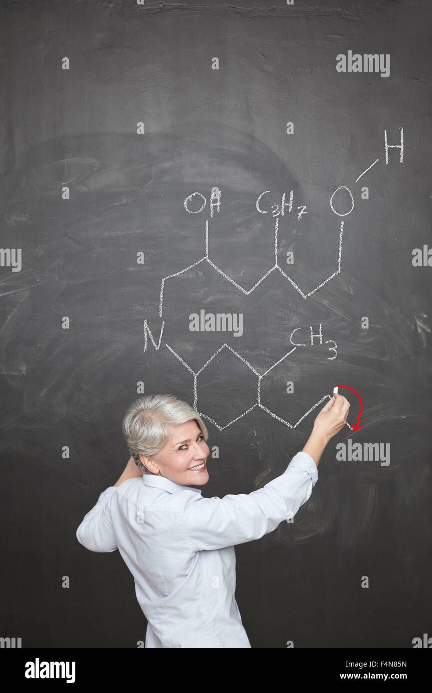 Reife Lehrer zeichnen chemische Formel auf Tafel Stockfoto