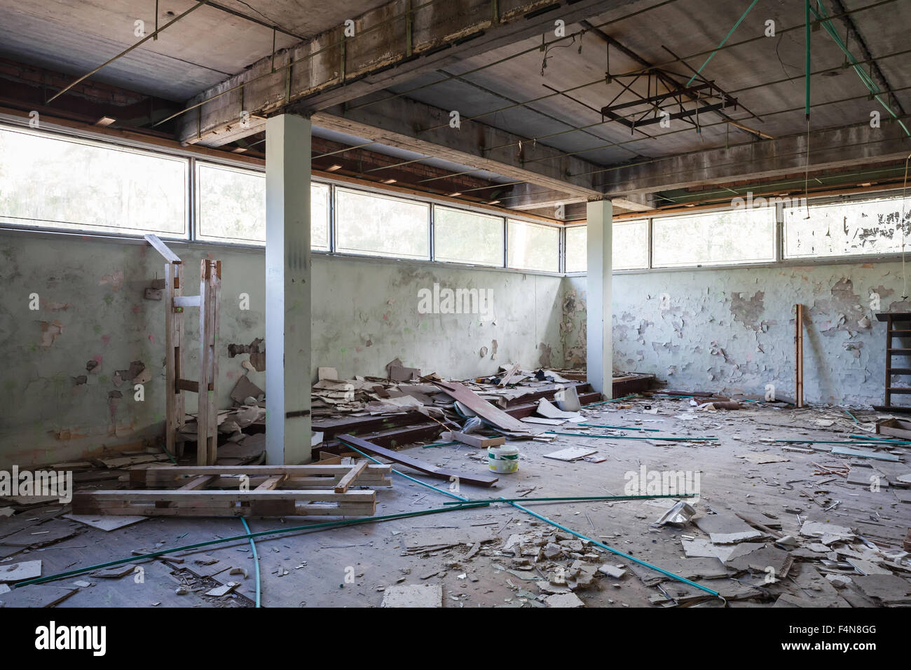 Verlassenes Industriegebäude Interieur. Halle mit Betonstützen und zerbrochenen Fensterscheiben Stockfoto