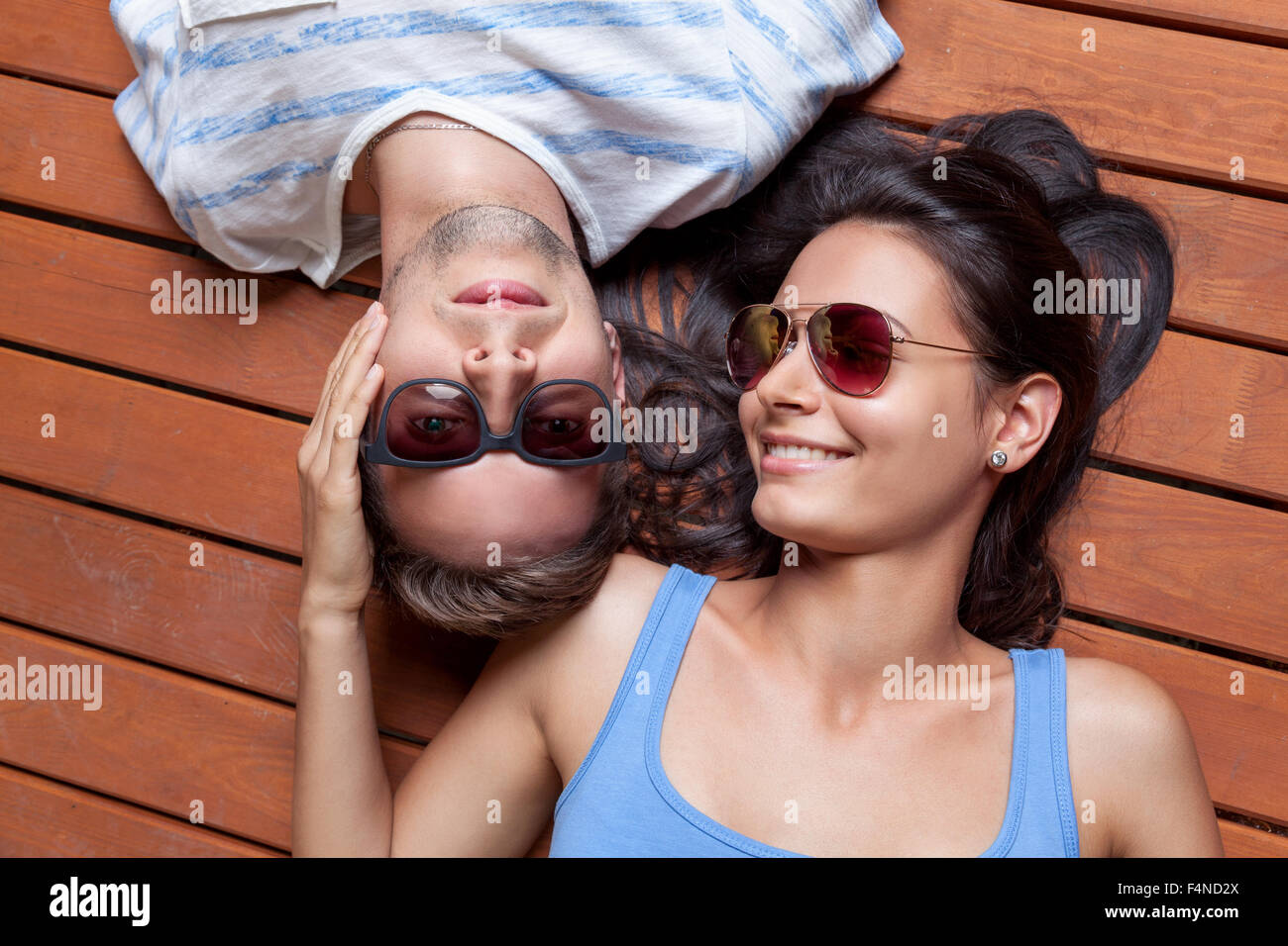 Glückliches junges Paar liegen Kopf an Kopf auf einem Holzfußboden Stockfoto