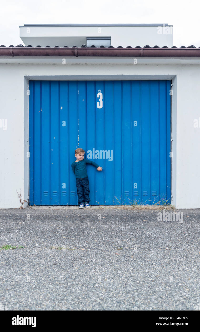 3 Jahre alter Junge vor Garagentor mit Nummer 3 Stockfoto