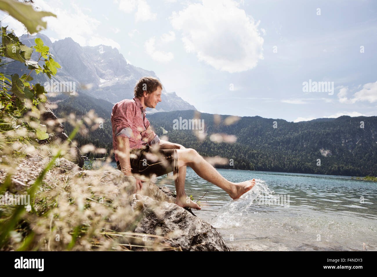 Deutschland, Bayern, Eibsee, lächelnd Mann in Lederhose planschen im Wasser Stockfoto