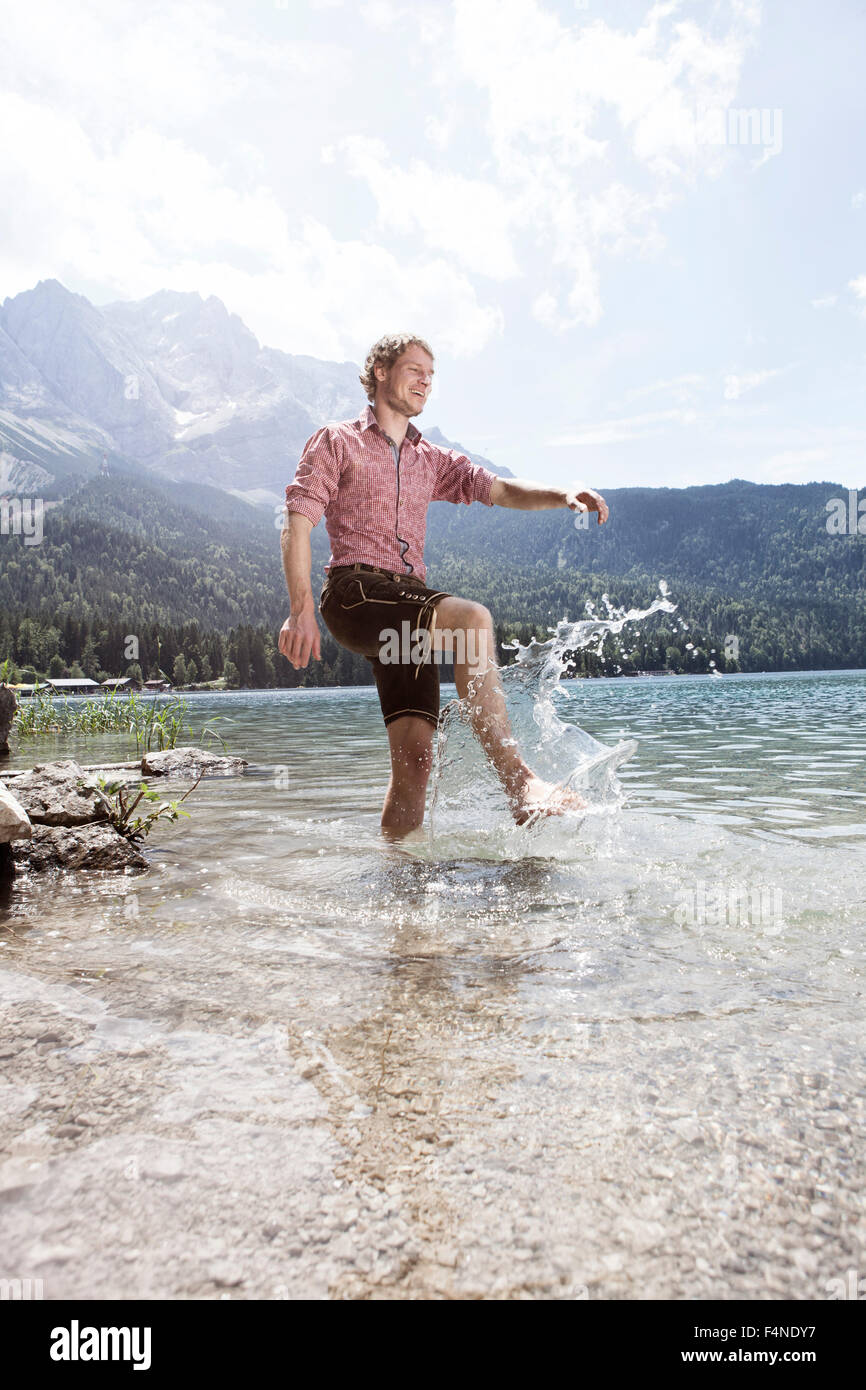 Deutschland, Bayern, Eibsee, glücklicher Mann in Lederhose planschen im Wasser Stockfoto