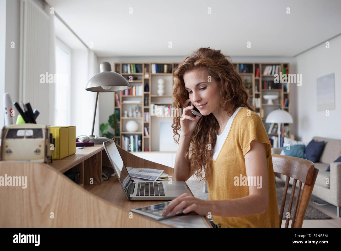 Frau zu Hause mit Handy, digitale Tablet und Laptop auf Sekretär Schreibtisch Stockfoto