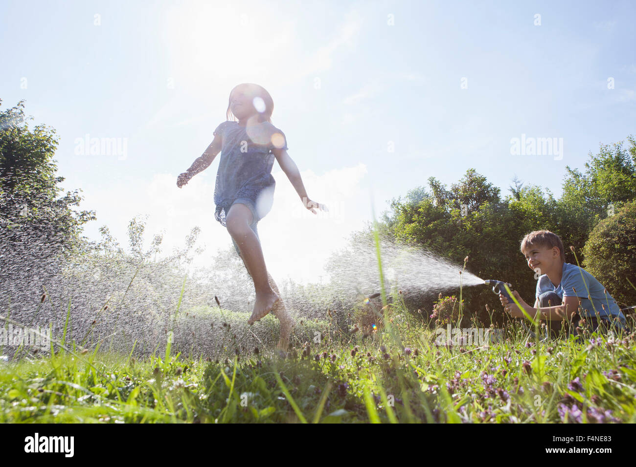 Jungen und Mädchen Spritzen mit Wasser im Garten Stockfoto