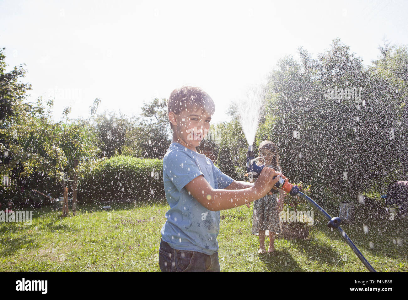 Jungen und Mädchen Spritzen mit Wasser im Garten Stockfoto