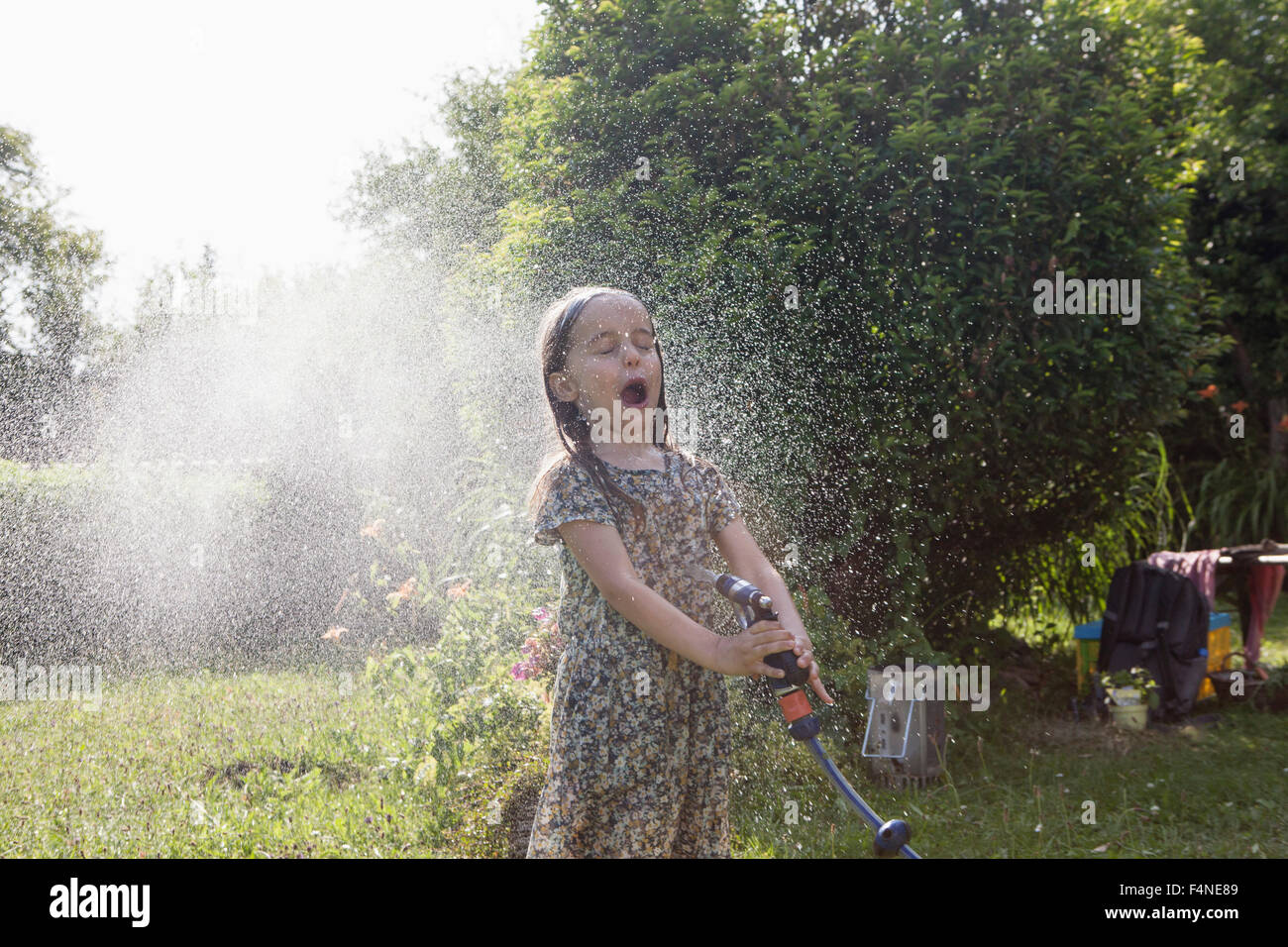 Mädchen Spritzen mit Wasser im Garten Stockfoto