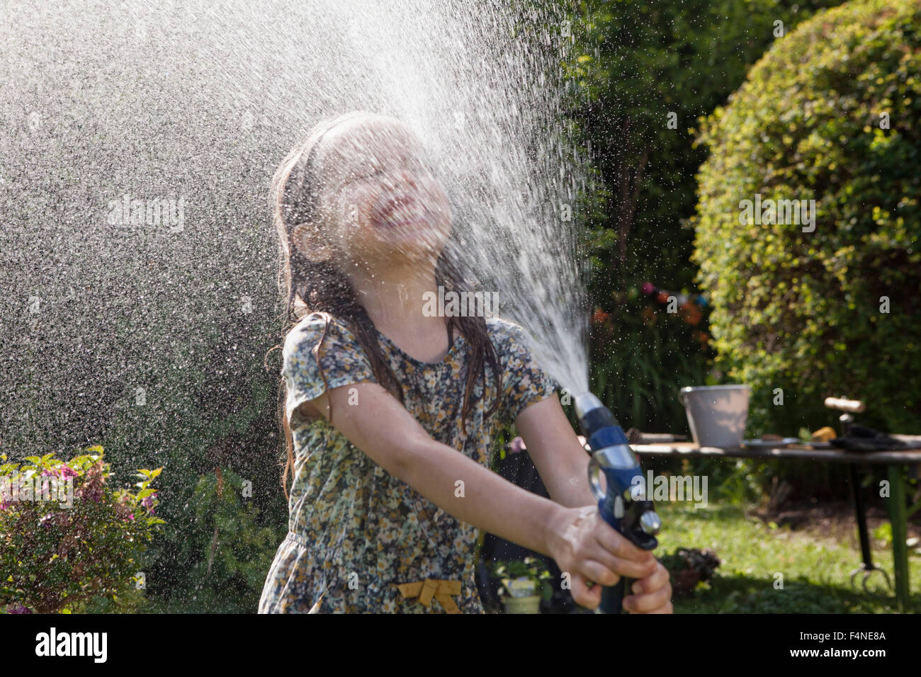 Mädchen Spritzen mit Wasser im Garten Stockfoto
