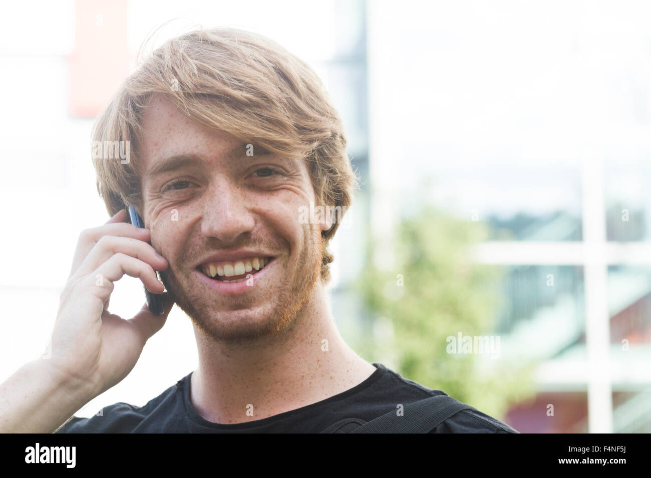 Porträt von lächelnden jungen Mann mit Smartphone telefonieren Stockfoto