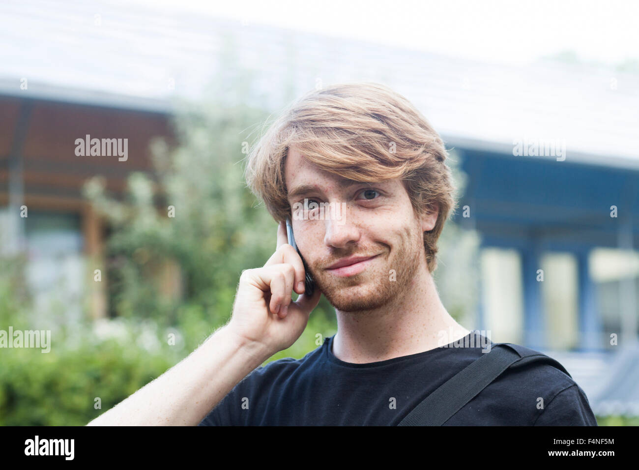 Porträt von lächelnden jungen Mann mit Smartphone telefonieren Stockfoto