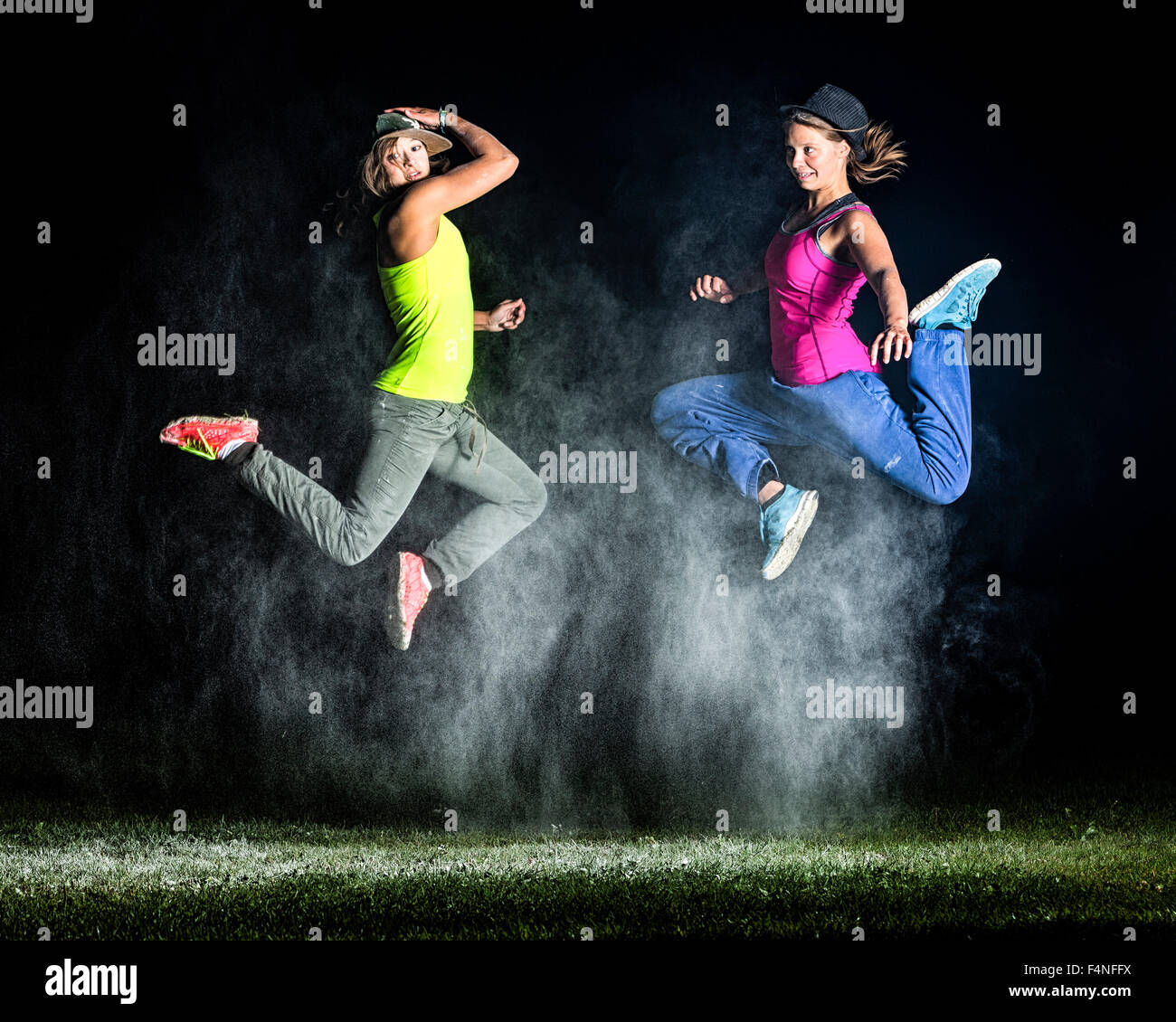 Zwei junge Frauen zwischen Wolke aus Mehl vor nächtlichen Himmel springen Stockfoto