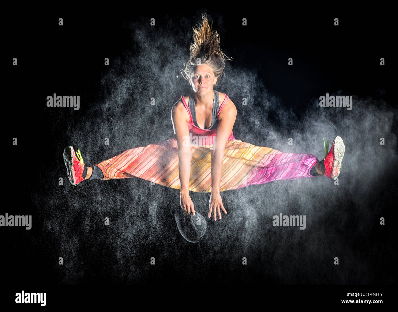 Junge Frau zwischen Wolke aus Mehl vor nächtlichen Himmel springen Stockfoto