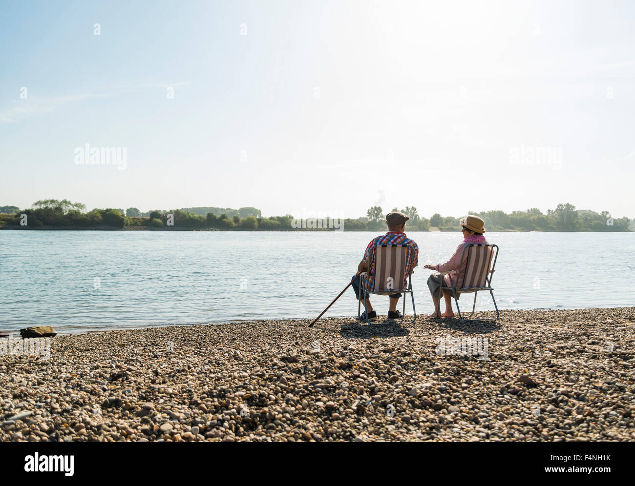 Deutschland, Ludwigshafen, Rückansicht älteres paar sitzen nebeneinander auf Klappstühlen im riverside Stockfoto