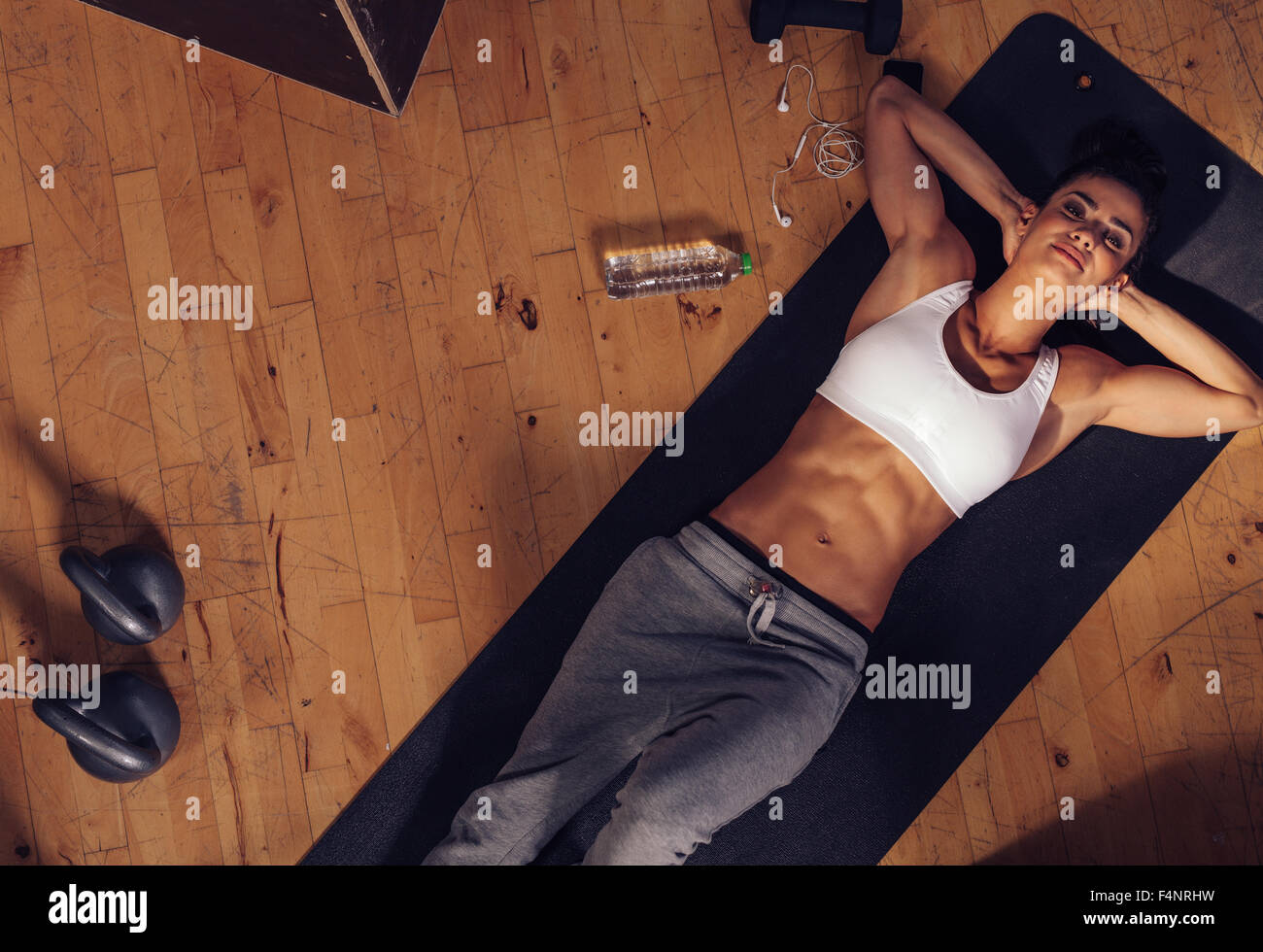 Draufsicht der entspannenden junge Frau, die auf Fitness-Matte liegen. Overhead Schuss Sportlerin, ruhen Sie sich nach intensivem Training mit Wasser Stockfoto