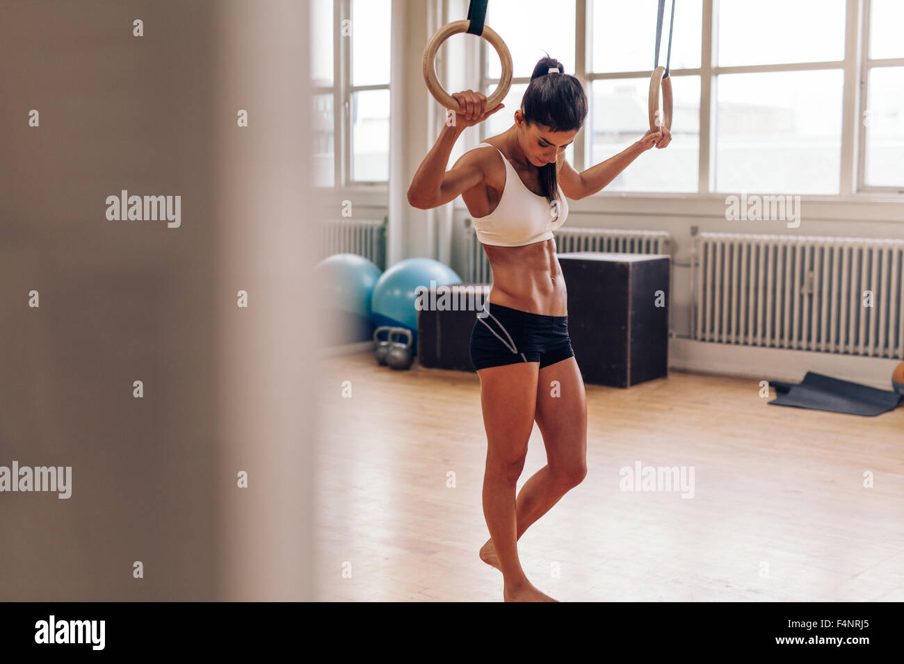 Muskulöse Frau Entspannung nach dem Training im Fitness-Studio.  Fitness-Frau Pause von Übung eintauchen. CrossFit Sprung Ring Übung. Stockfoto
