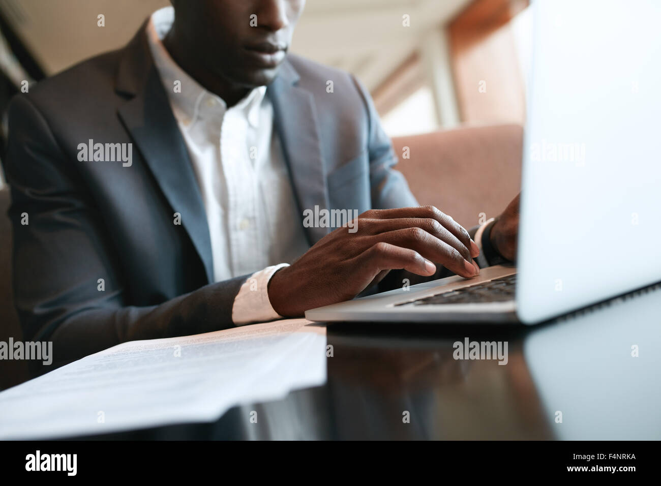 Schuss von männlichen Händen tippen auf Laptoptastatur hautnah. Afrikanische Unternehmer arbeiten auf Laptop-Computer im Café. Stockfoto