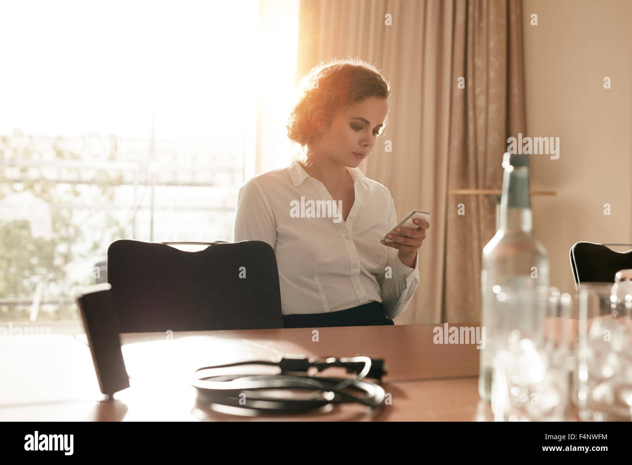Bild der Geschäftsfrau am Konferenztisch SMS auf ihrem Handy lesen. Kaukasische weiblichen Vorstand sitzen allein am Stockfoto