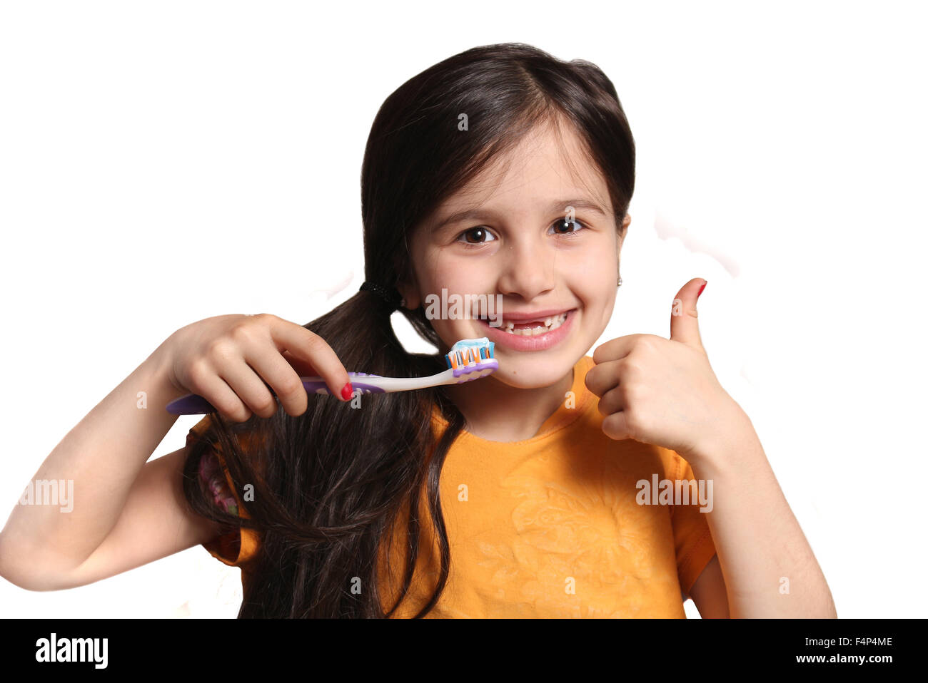 Sieben Jahres altes Mädchen zeigt großes Lächeln zeigt, fehlen die oberen Schneidezähne und halten eine Zahnbürste mit Zahnpasta und Daumen u Stockfoto