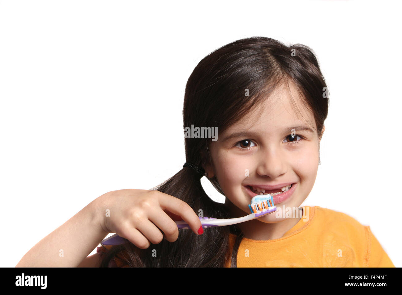 Sieben Jahres altes Mädchen zeigt großes Lächeln zeigt, fehlen die oberen Schneidezähne und halten eine Zahnbürste mit Zahnpasta auf einem weißen b Stockfoto