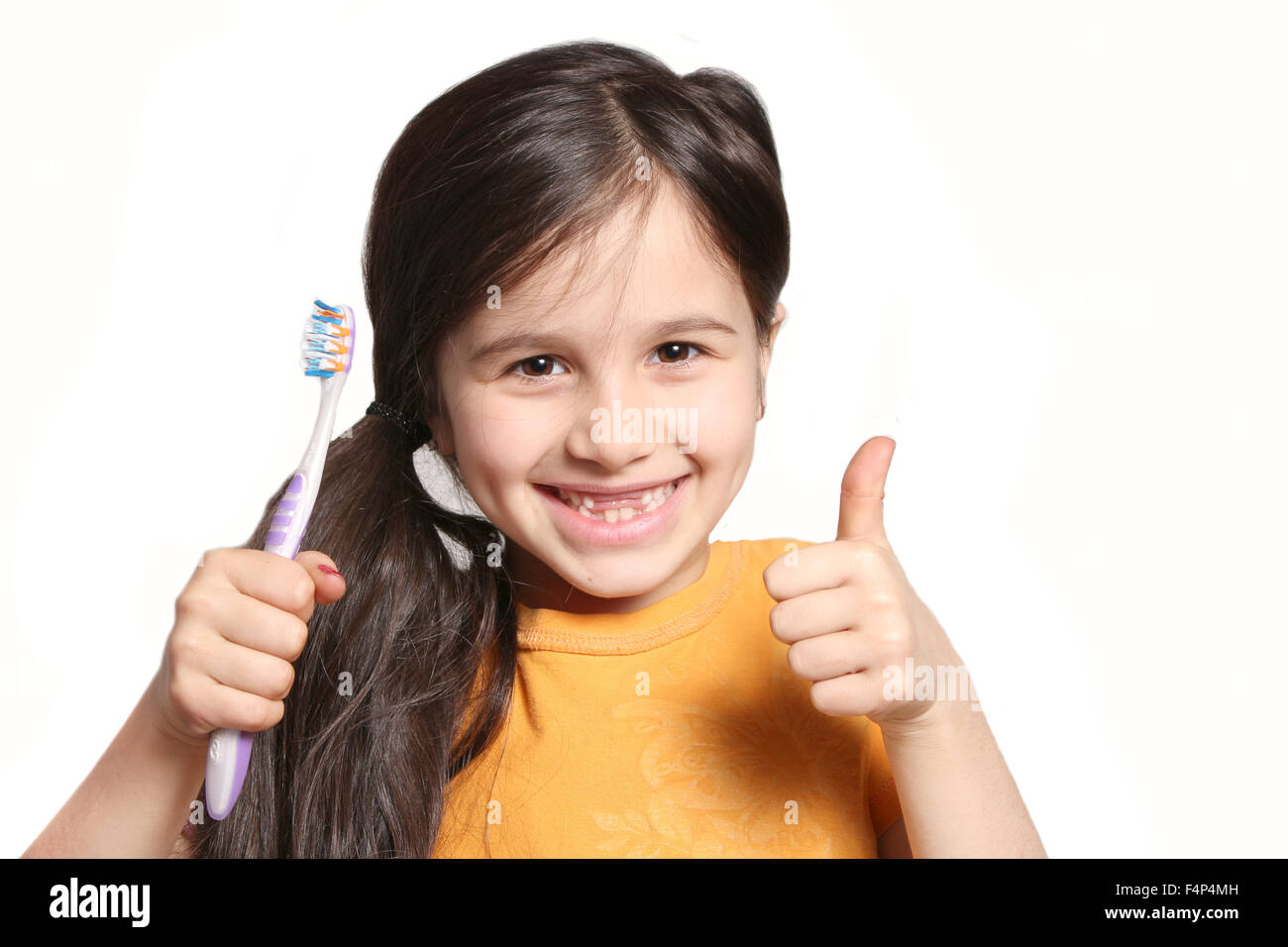 Sieben Jahres altes Mädchen zeigt großes Lächeln zeigt, fehlen die oberen Schneidezähne und halten eine Zahnbürste auf weißem Hintergrund Stockfoto