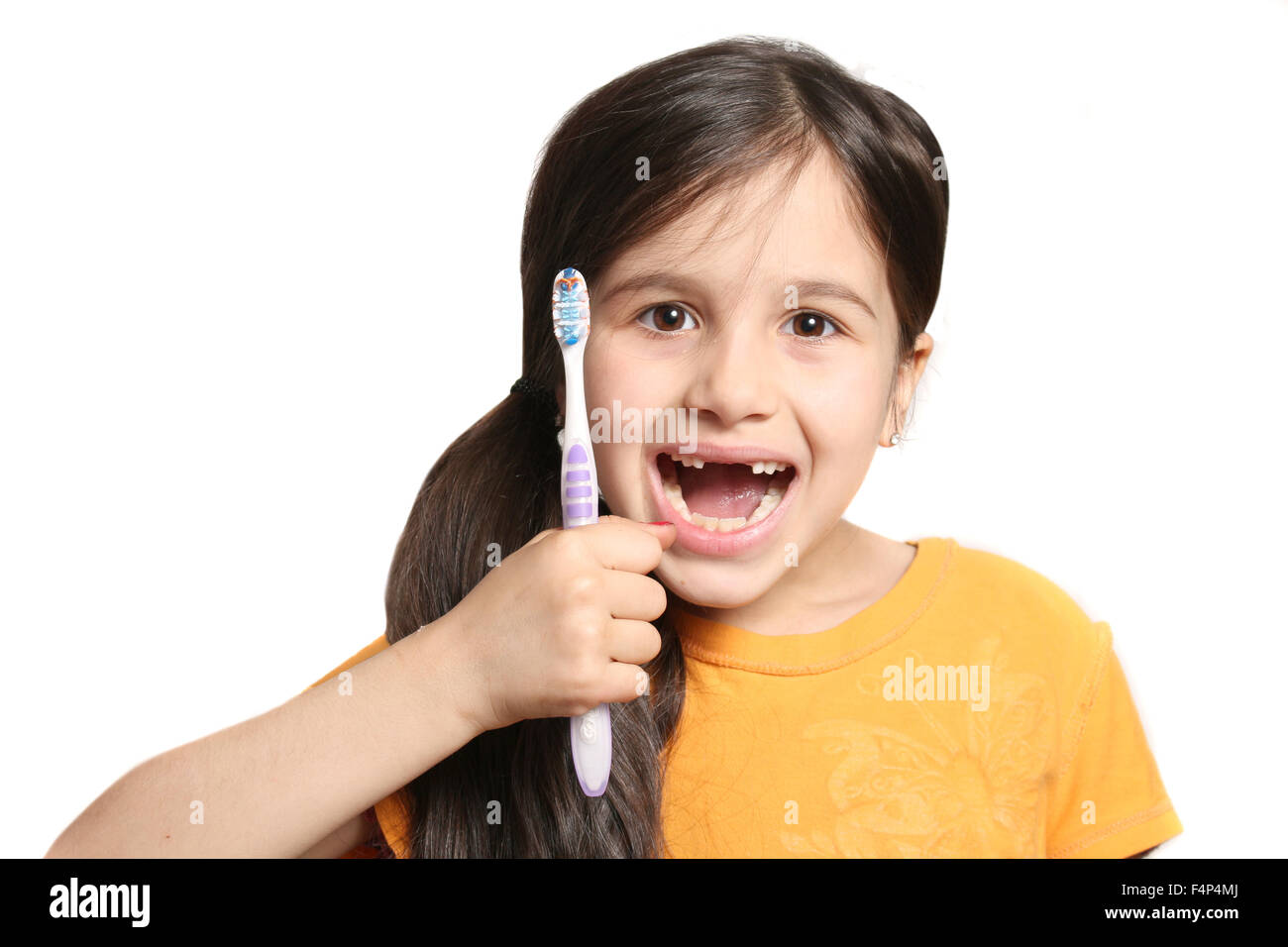Sieben Jahres altes Mädchen zeigt großes Lächeln zeigt, fehlen die oberen Schneidezähne und halten eine Zahnbürste auf weißem Hintergrund Stockfoto