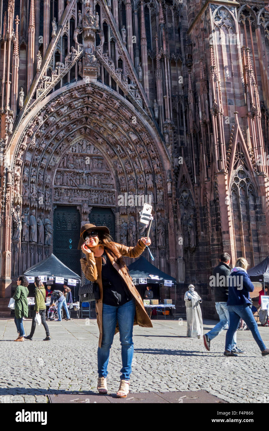 Asiatische Frau unter Selbstbildnis mit Smartphone auf Selfie-Stick vor der Kathedrale von unserer lieben Frau von Straßburg, Frankreich Stockfoto
