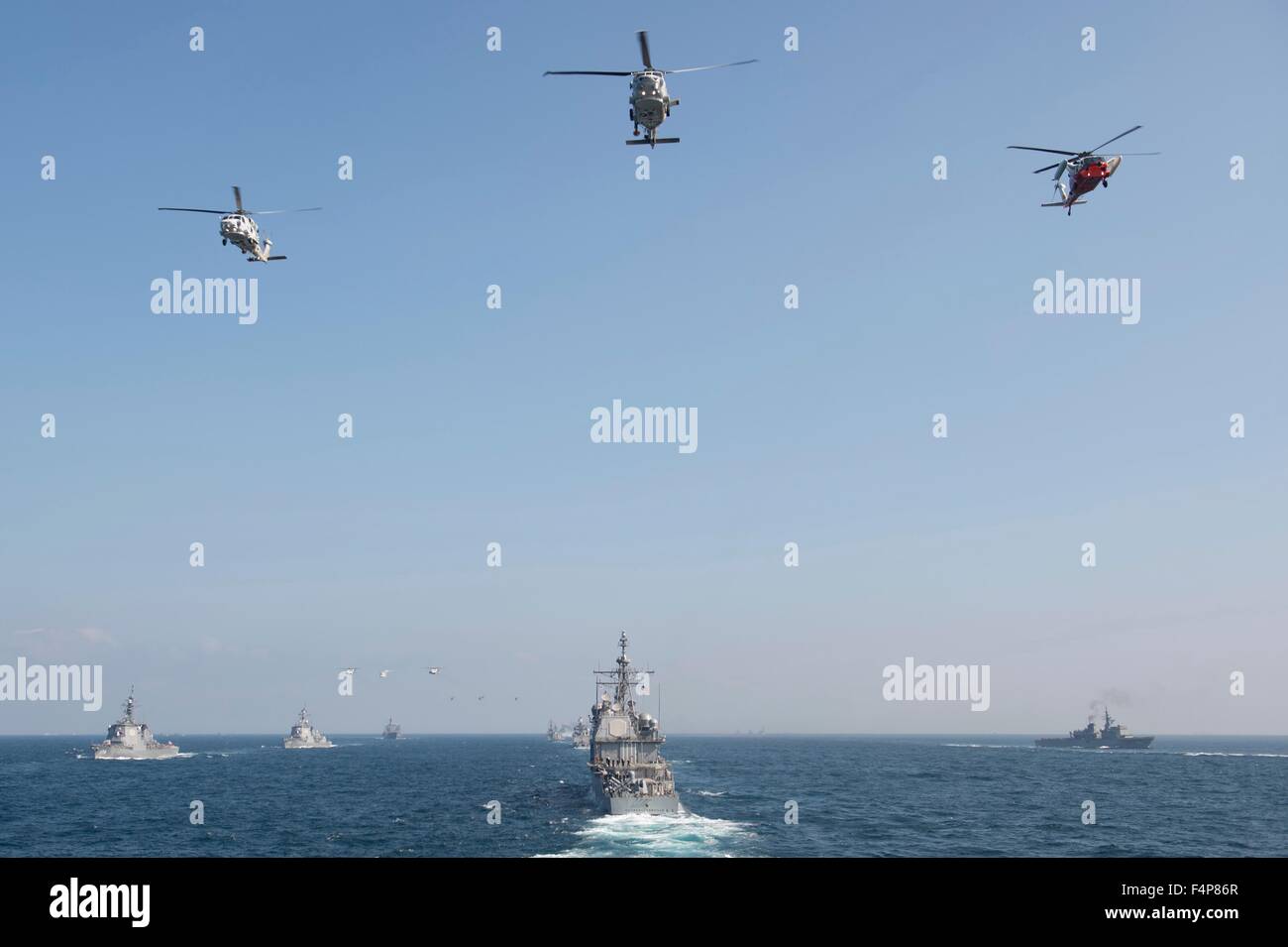 US Navy Hubschrauber überfliegen der Ticonderoga-Klasse geführte Flugkörper Kreuzer USS Chancellorsville während eines Durchgangs und überprüfen mit Schiffen aus verschiedenen Ländern in der Indo-Asien-Pazifik-Region 18. Oktober 2015 in der Sea Of Japan. Stockfoto