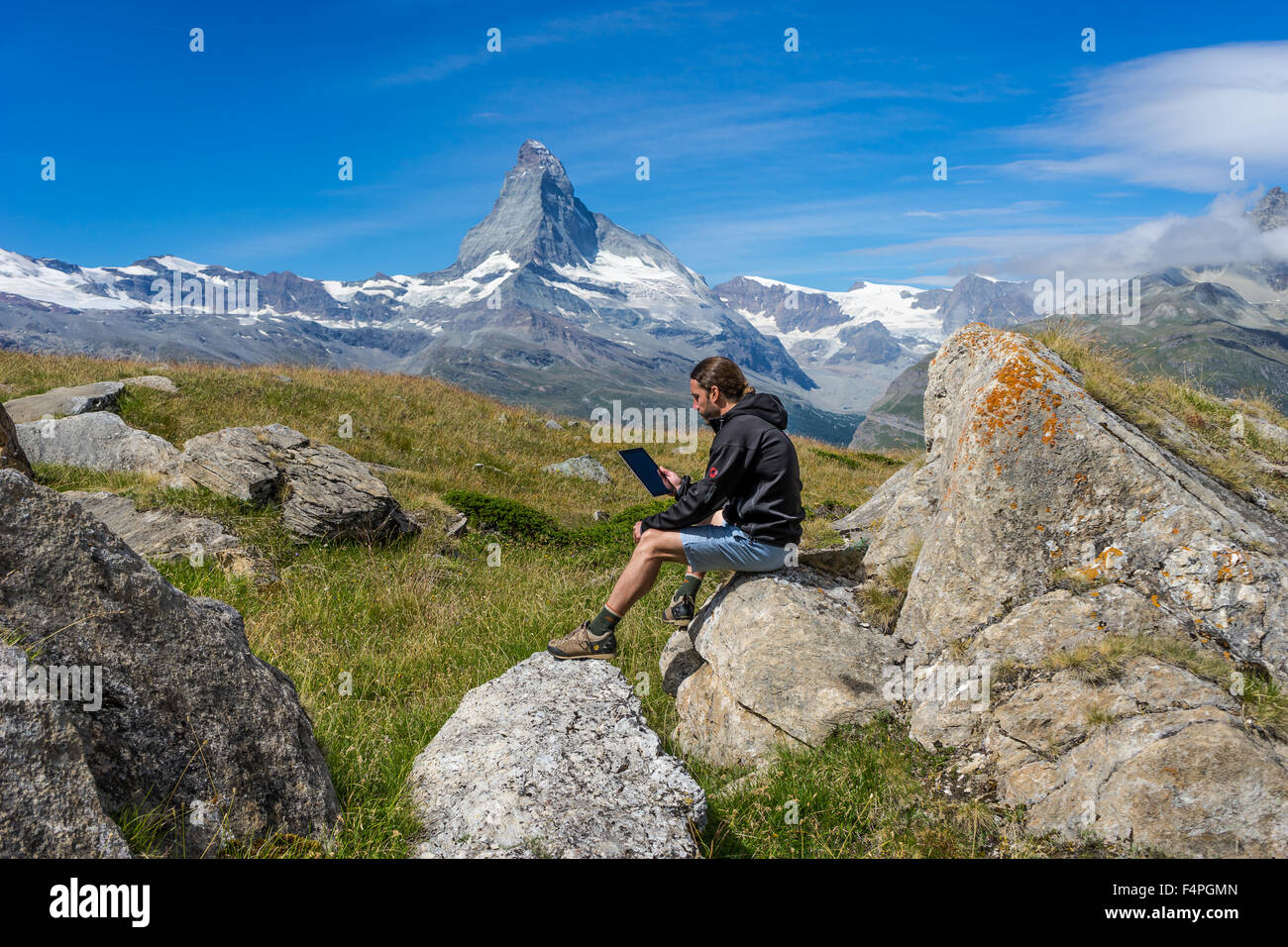 Robuste Wanderer liest aus einem smart Tablet unter Matterhorn Gipfel. Juli 2015. Matterhorn, Schweiz. Stockfoto