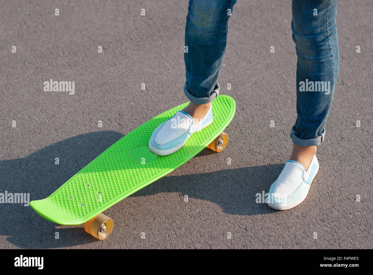 Teenager in Jeans mit einem Skateboard auf der Straße. Stockfoto