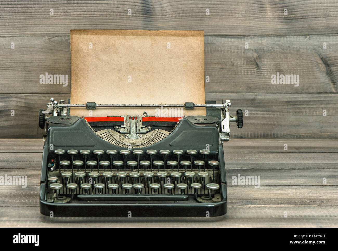 Antike Schreibmaschine mit Grunge Papier auf Holz Hintergrund. Retro-Stil getönt Bild. Selektiven Fokus Stockfoto
