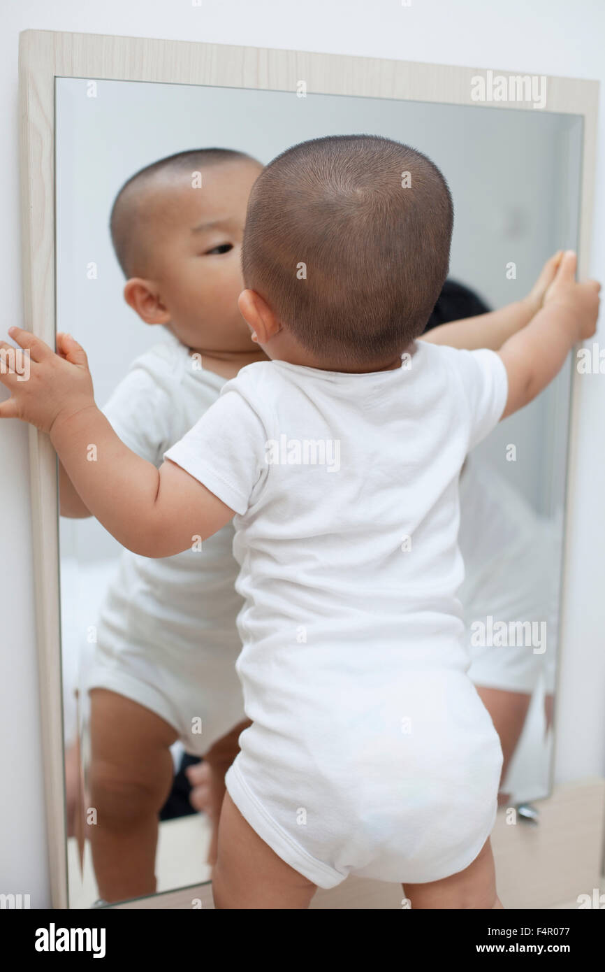 Niedliche chinesischen baby jungen spielt vor einem Spiegel Stockfoto