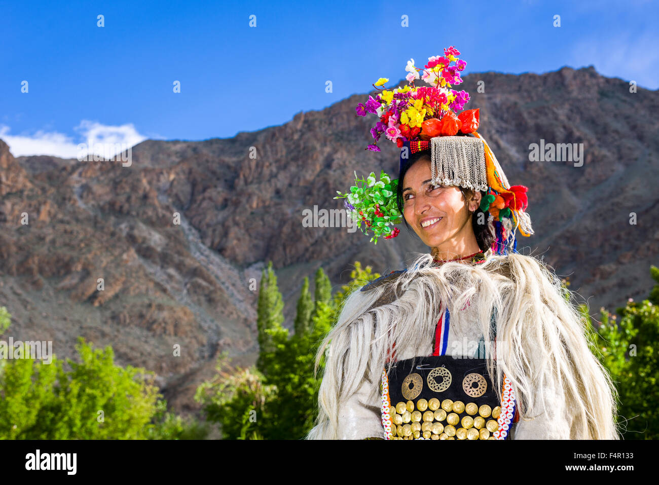 Eine Frau aus dem Stamm der Brokpa, Arien Rennen, in dem traditionellen Gewand mit einem Blumenarrangement auf dem Kopf durchgeführt Stockfoto