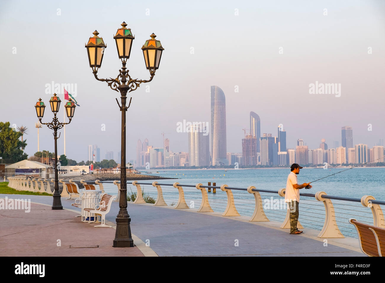 Mann Angeln vom Corniche mit Blick auf Skyline von Abu Dhabi Vereinigte Arabische Emirate Stockfoto