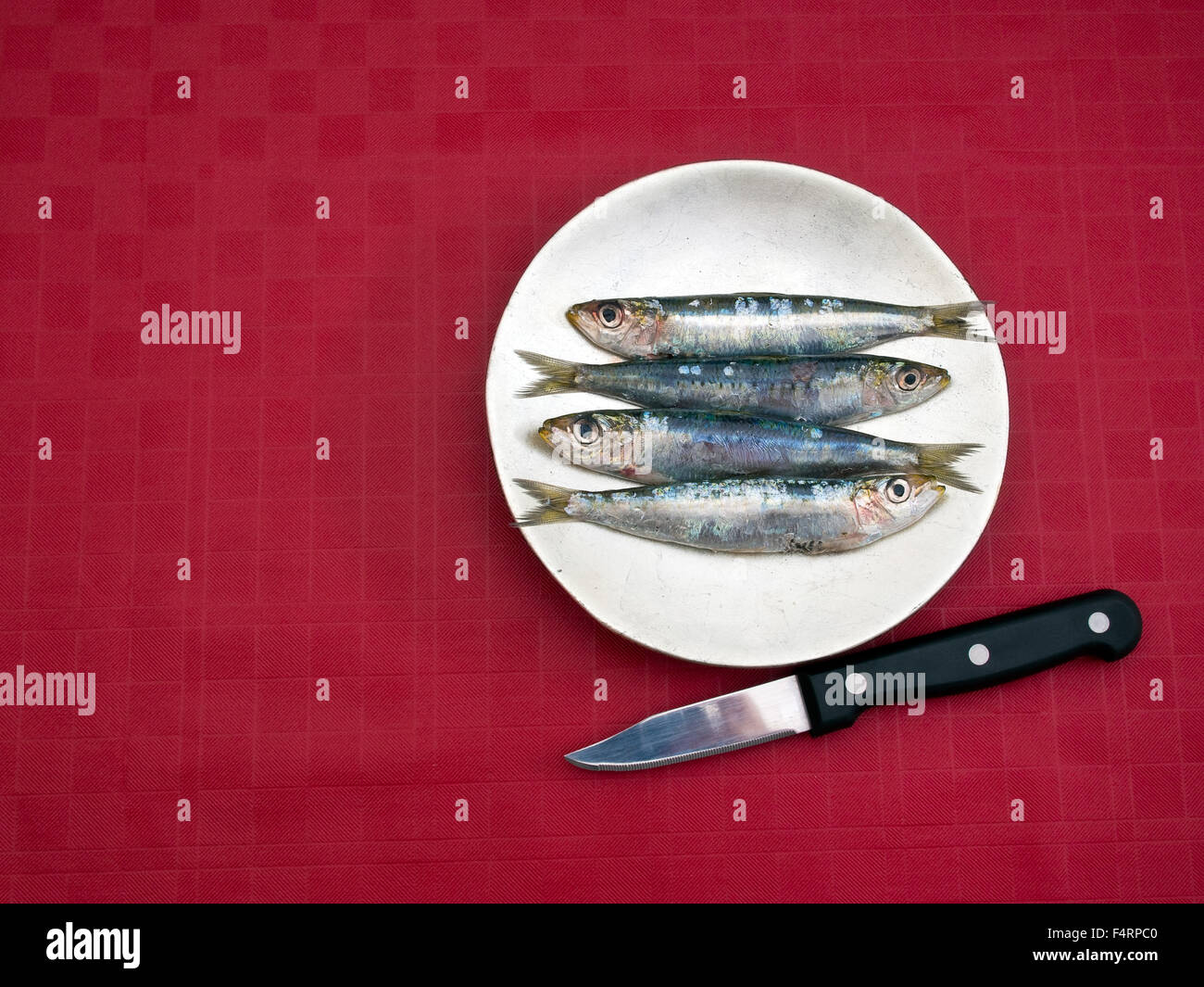 Gesunden Fetten Fisch aka Sardinen. Auf Platte Wth Kife. Roten Tischdecke. Stockfoto
