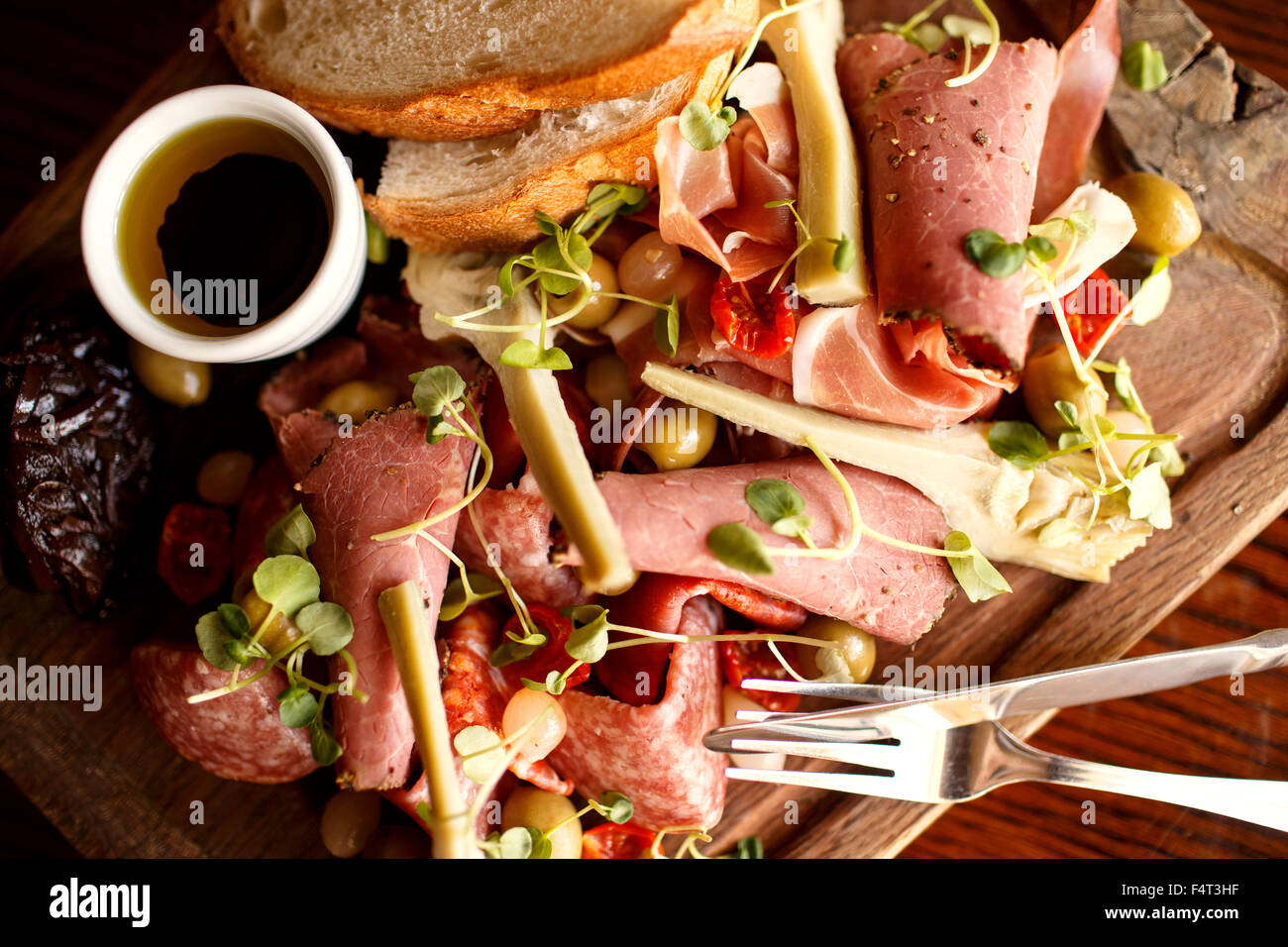 Eine mediterrane Fleisch Platte mit Schinken, Brot, Oliven, Artischocken, getrockneten Tomaten und eingelegte Zwiebeln Stockfoto