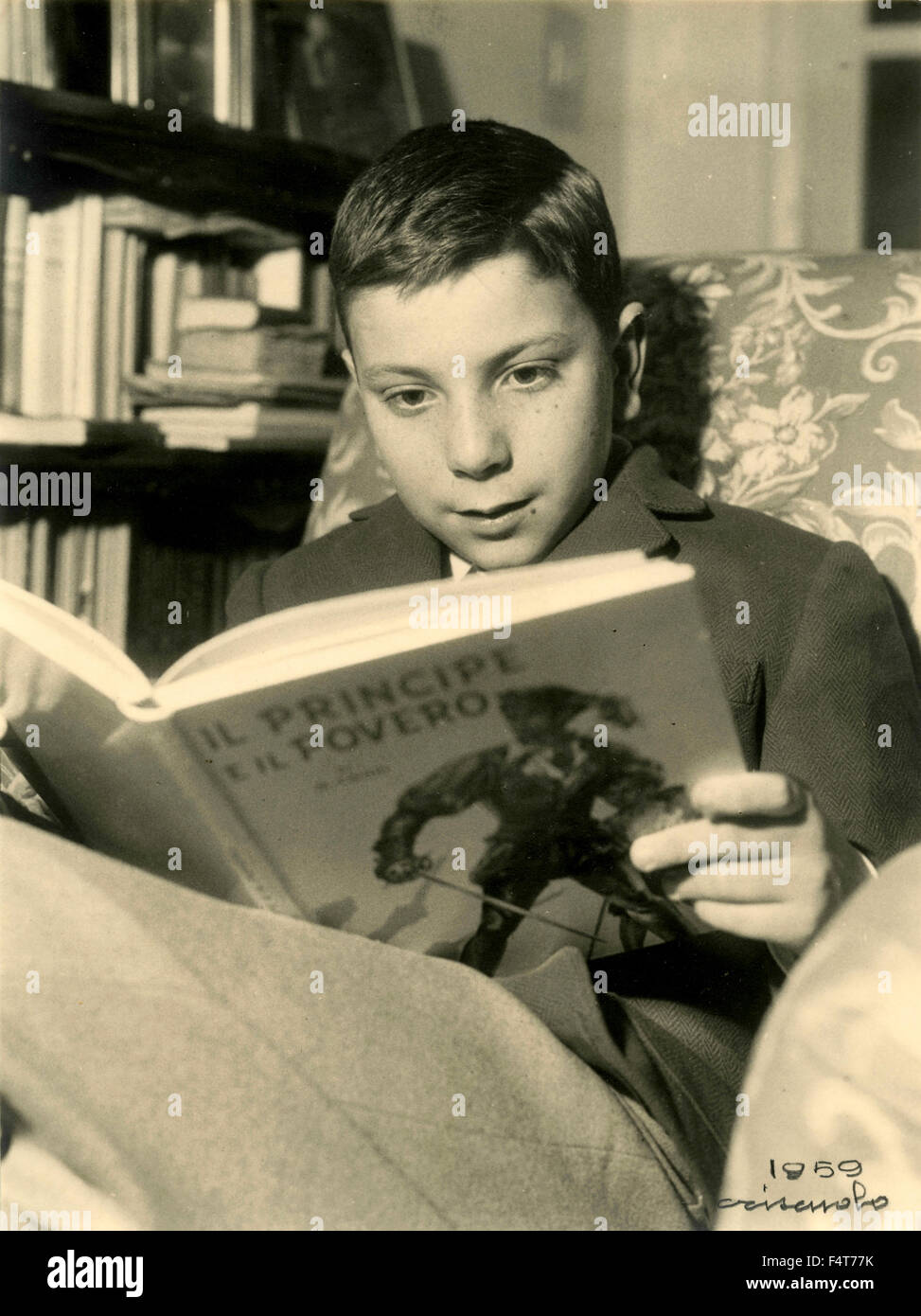 Ein Kind sitzt in einem Sessel, die Lektüre des Buches "The Prince and the Pauper" Stockfoto