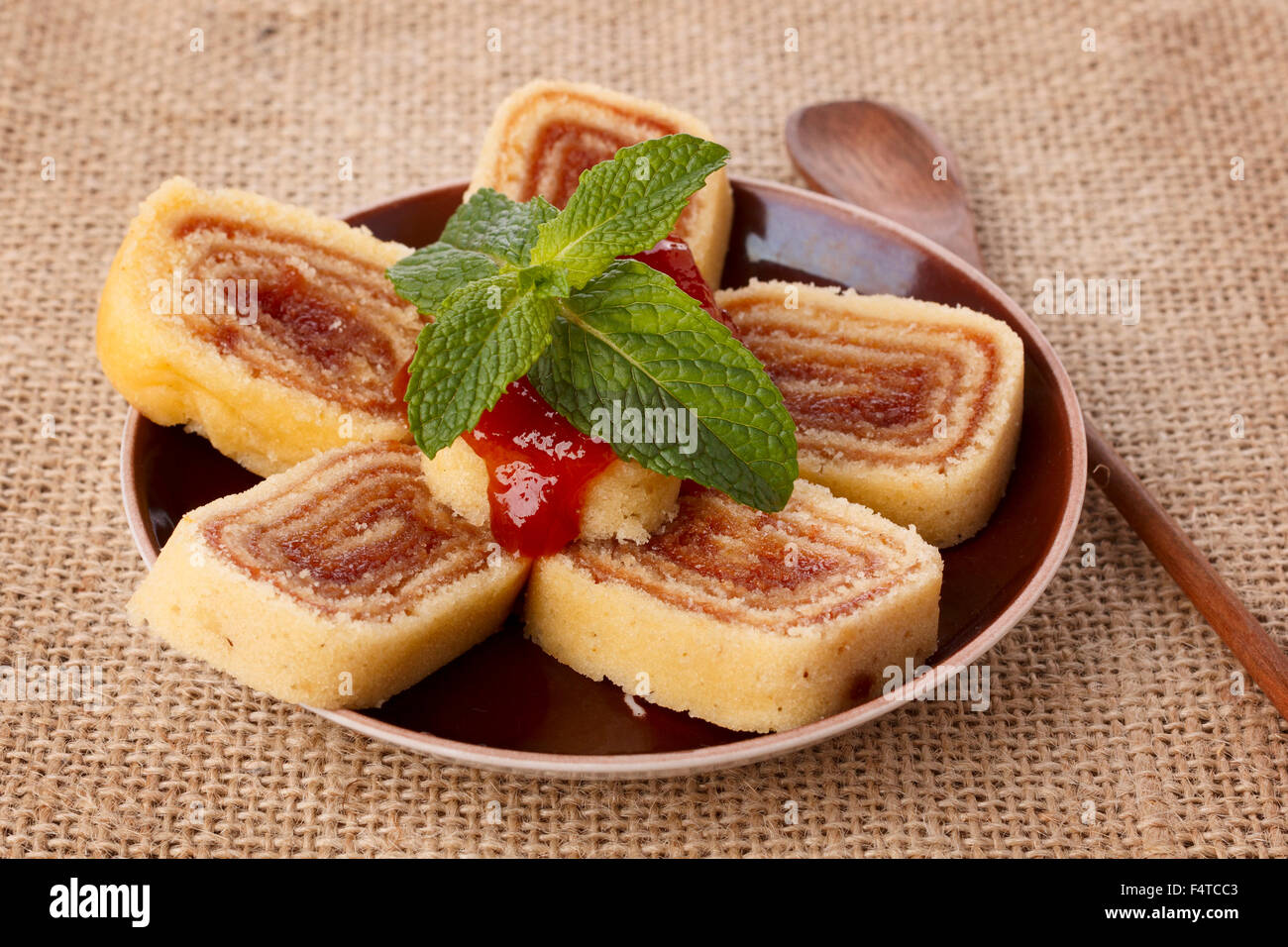 Bolo de Rolo (Swiss Roll, Roll Kuchen) brasilianischen Dessert auf braune Teller auf Sackleinen. Selektiven Fokus Stockfoto