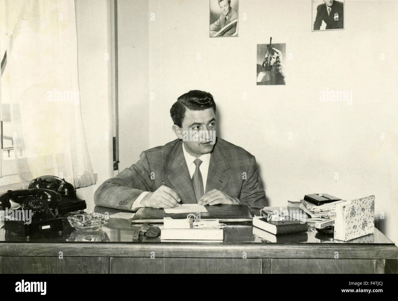 Ein Mann arbeitet auf einem Schreibtisch mit zwei Telefonen Stockfoto