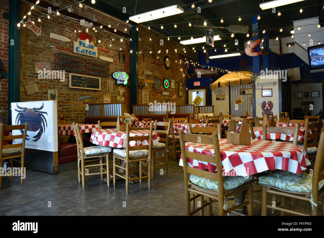 Ein retro und coole alte historische rustikales Fischrestaurant mit Menüs auf der Wand Ziegel und ausgestattet mit roten & weiße Tischdecken Stockfoto