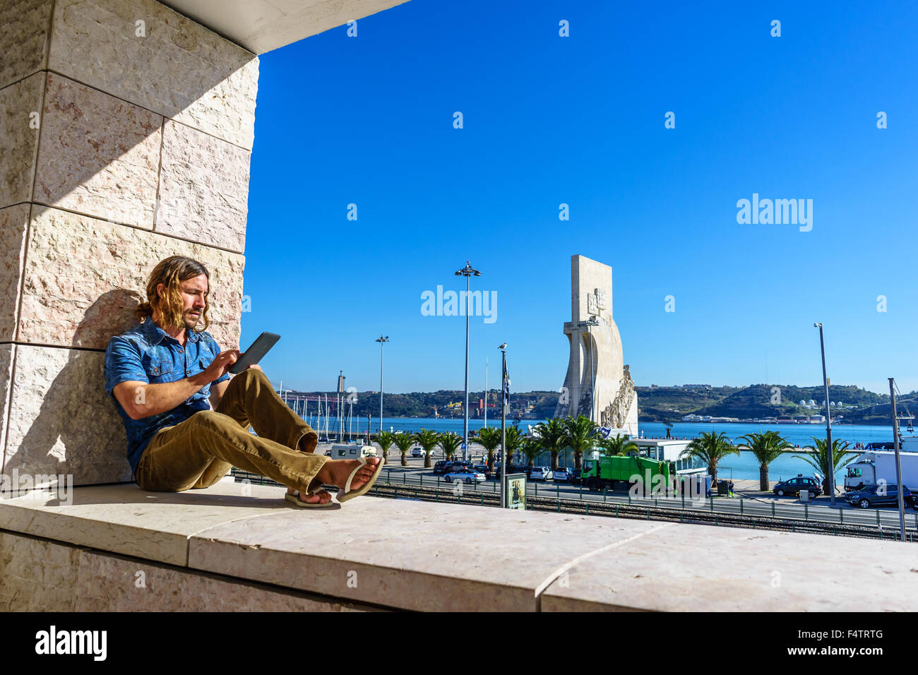 Man liest aus einem elektronischen Tablet vor der portugiesischen Ikone, Denkmal der Entdeckungen Padrão Dos Descobrimentos. Stockfoto