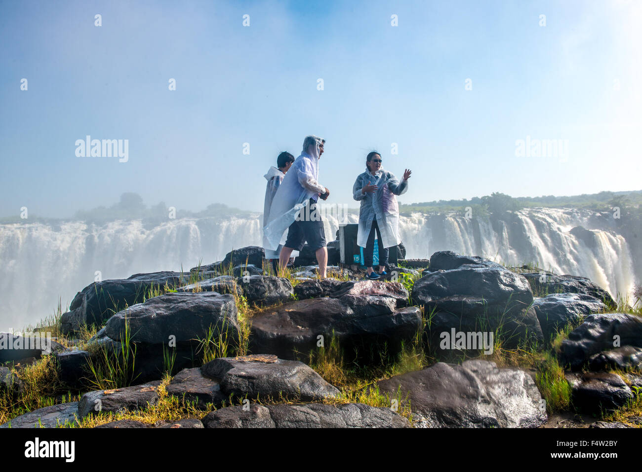 Viktoriafälle, Simbabwe - Touristen mit Regenponchos neben Victoria Falls Wasserfall. Stockfoto