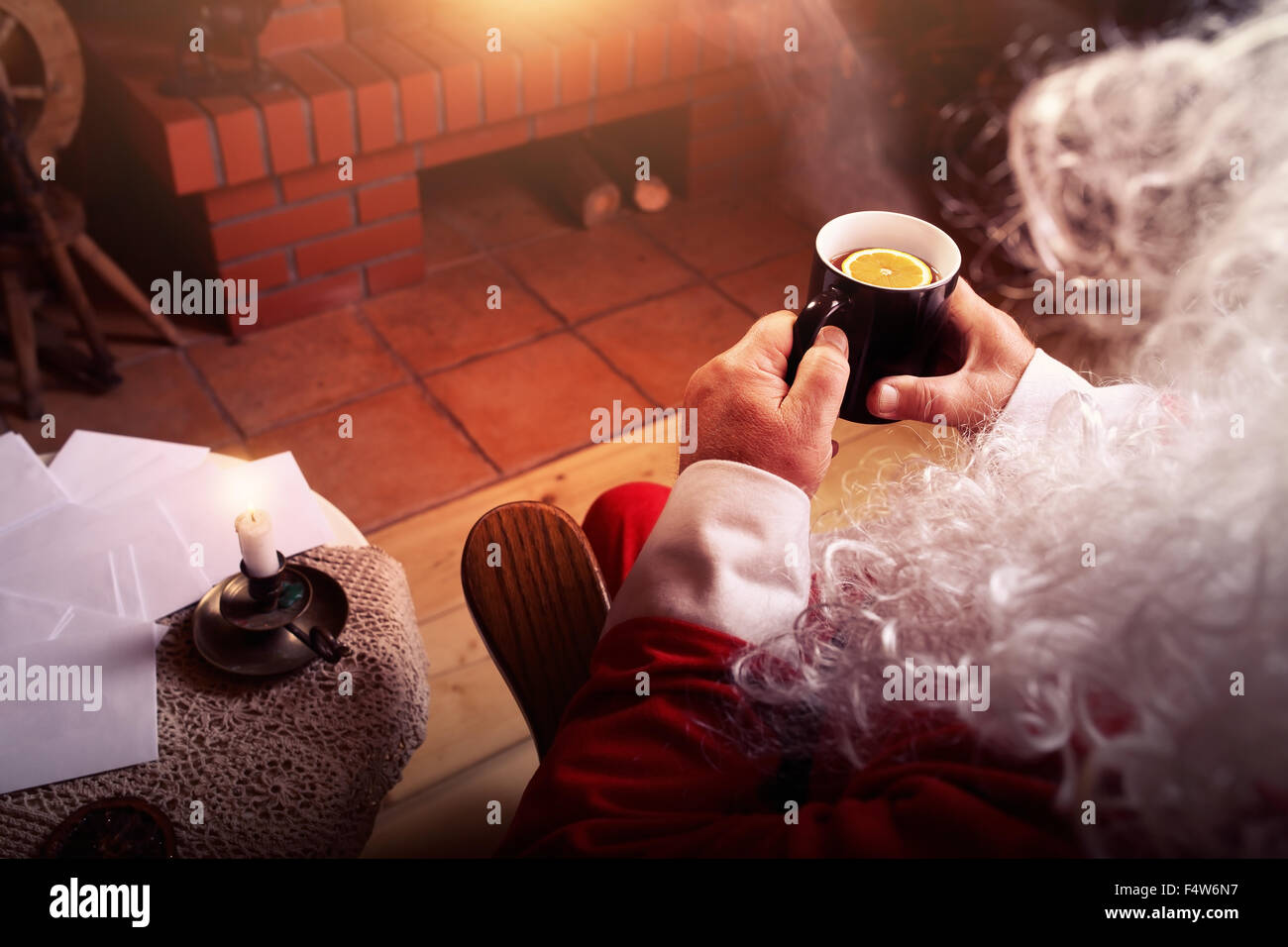 Santa Claus ruht in Hütte mit Kamin und heißen Tee mit Zitrone Stockfoto