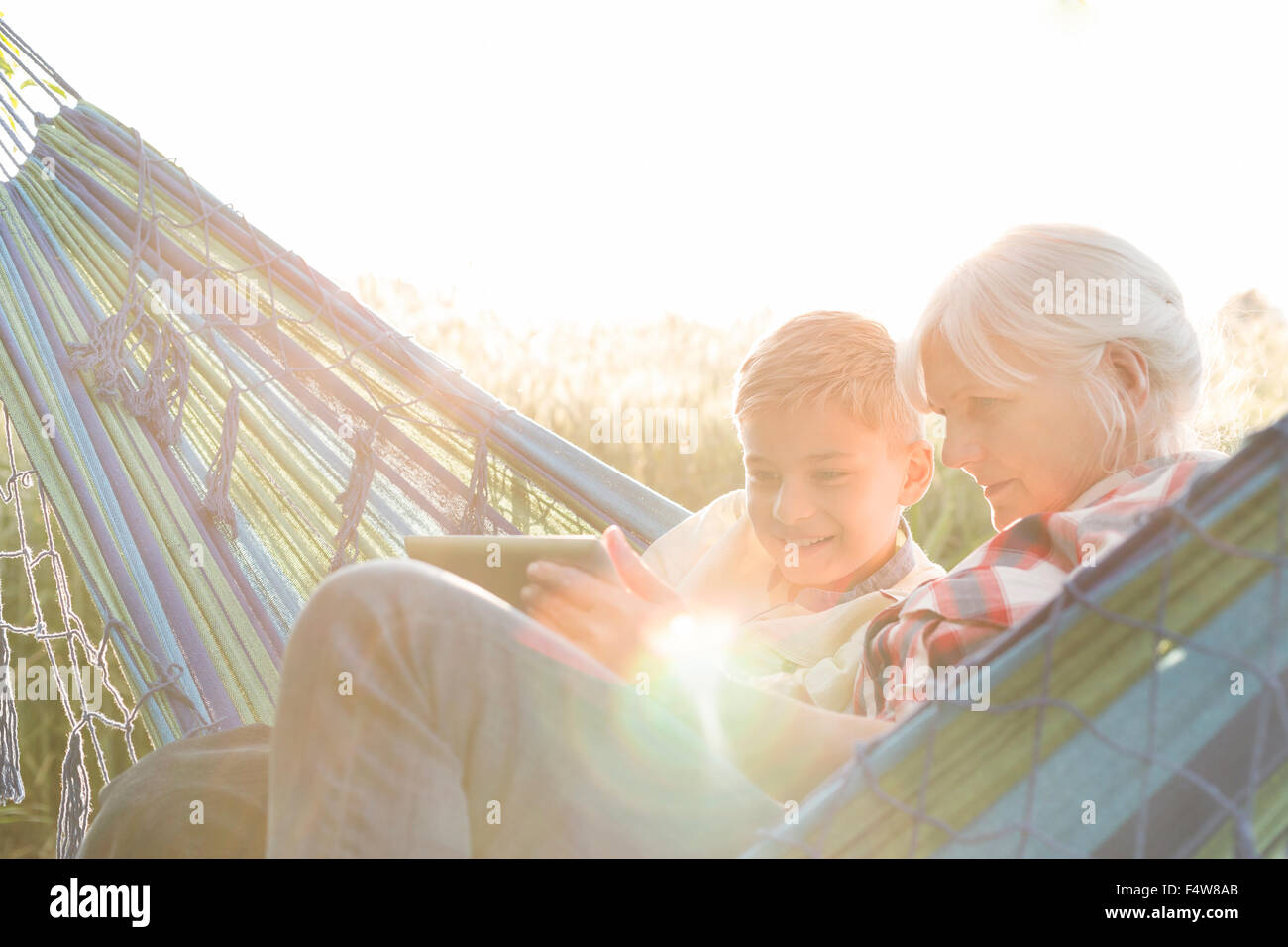 Großmutter und Enkel mit digital-Tablette in sonniger Hängematte Stockfoto