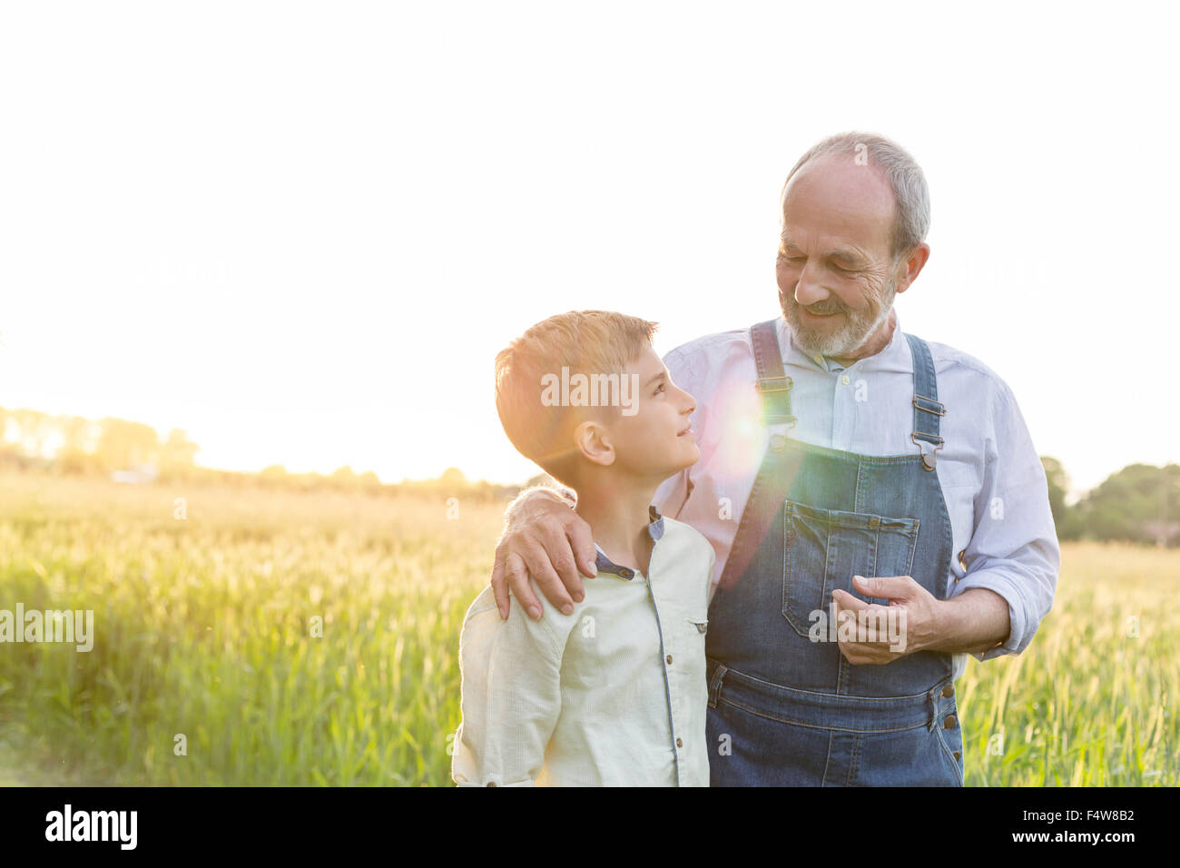 Landwirt Großvater und Enkel umarmt in ländlichen Weizenfeld Stockfoto