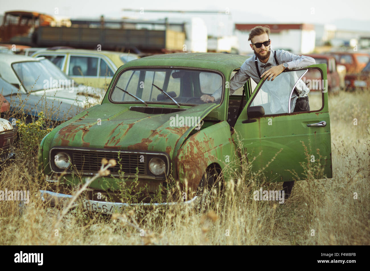 Porträt von einem stilvollen schönen jungen Mann, in Hemd und Sonnenbrille, altes Auto fahren Stockfoto